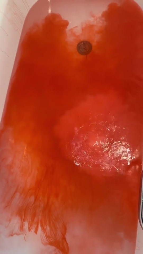 a bathtub with red liquid coming out of the drain