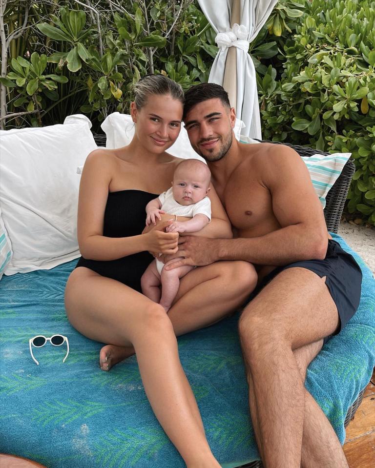 a man and a woman sitting on a couch holding a baby