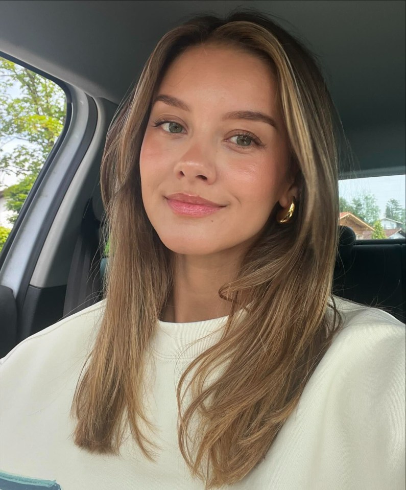 a woman wearing a white shirt and gold hoop earrings smiles for the camera