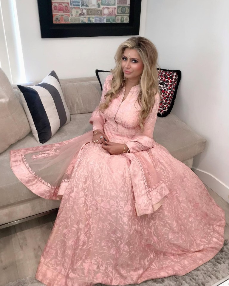 a woman in a long pink dress sits on a couch