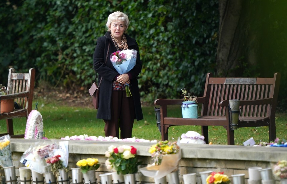 a woman holds a bouquet of flowers in front of a wooden bench