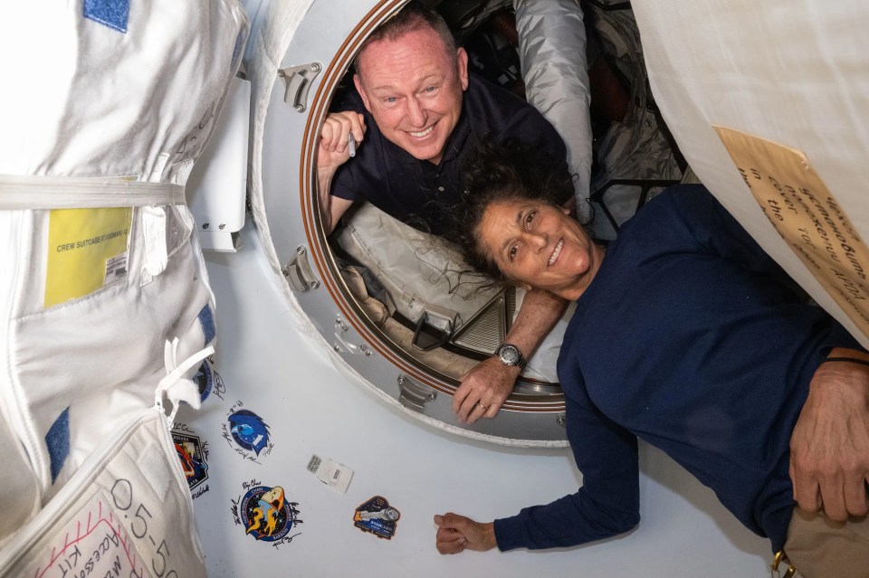 a man and a woman are looking out of a space shuttle window