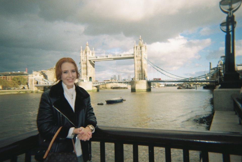 a woman stands in front of the tower bridge in london