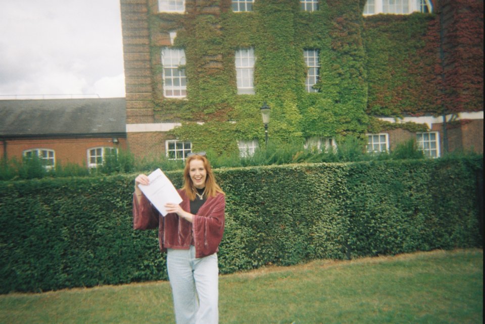 a woman holding a piece of paper in front of a building