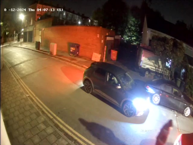 a black car is parked on the side of the road at night