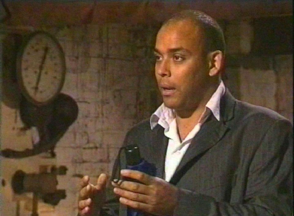 a man in a suit is holding a bottle in front of a clock .