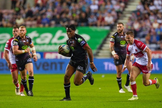 a rugby player with lcs on his shorts is running with the ball