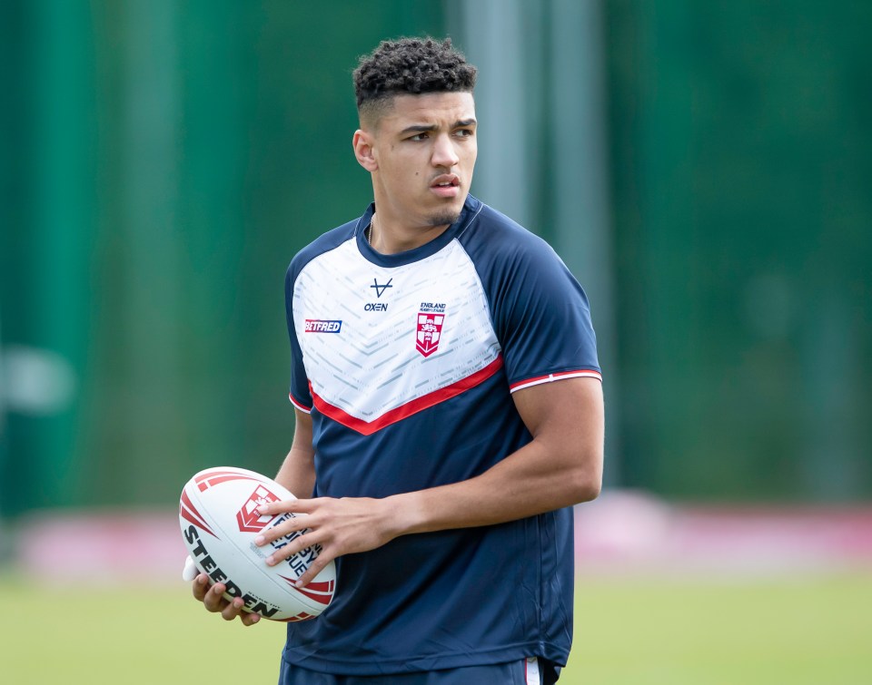 a young man holding a rugby ball wearing a crew jersey
