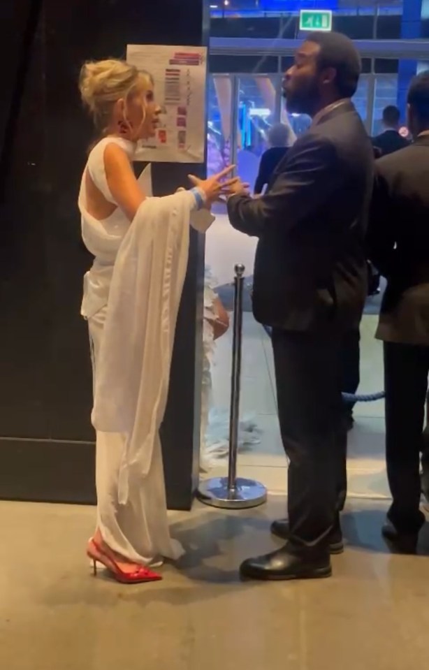 a woman in a white dress is talking to a man in a suit