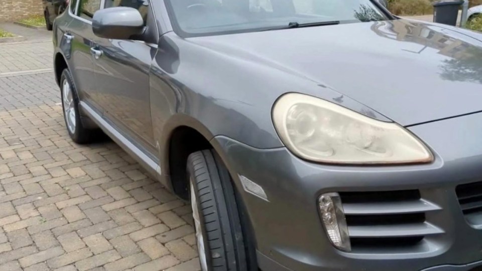 a gray car is parked on a brick driveway