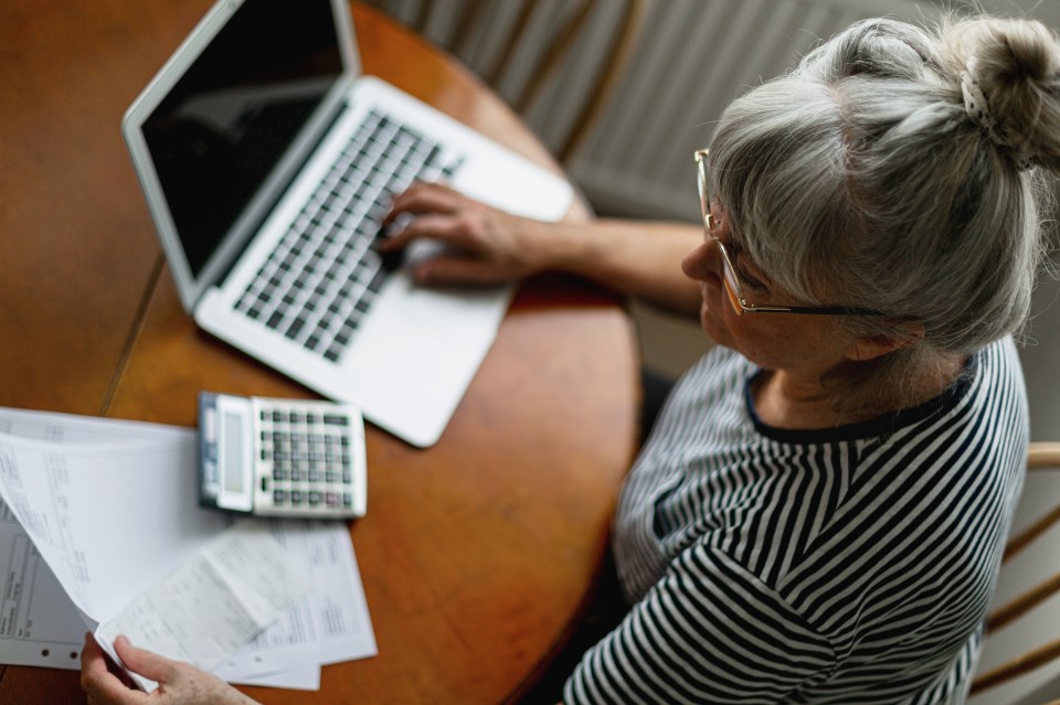 a woman sits at a table with a laptop and a calculator