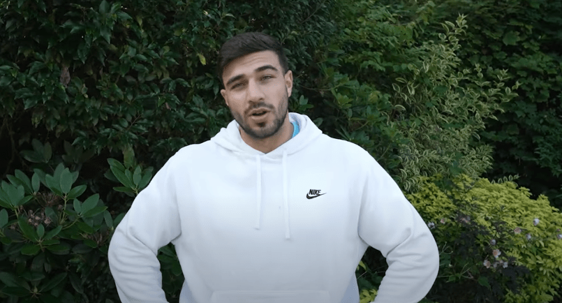 a man wearing a white nike hoodie stands in front of trees