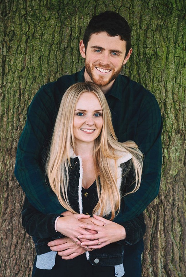 a man and woman are posing for a picture in front of a tree