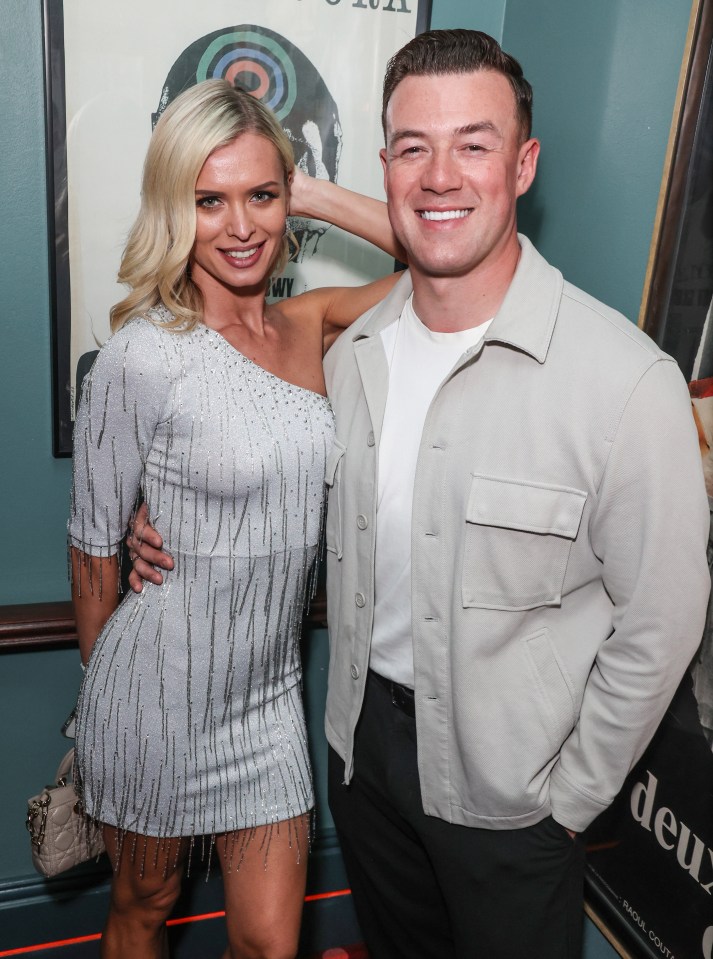 a man and a woman pose in front of a poster that says deux