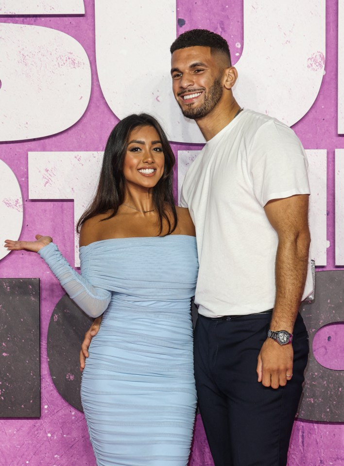 a man and a woman pose for a picture on a purple carpet