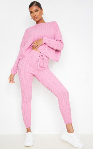 a model is wearing a pink knitted sweater and joggers set .