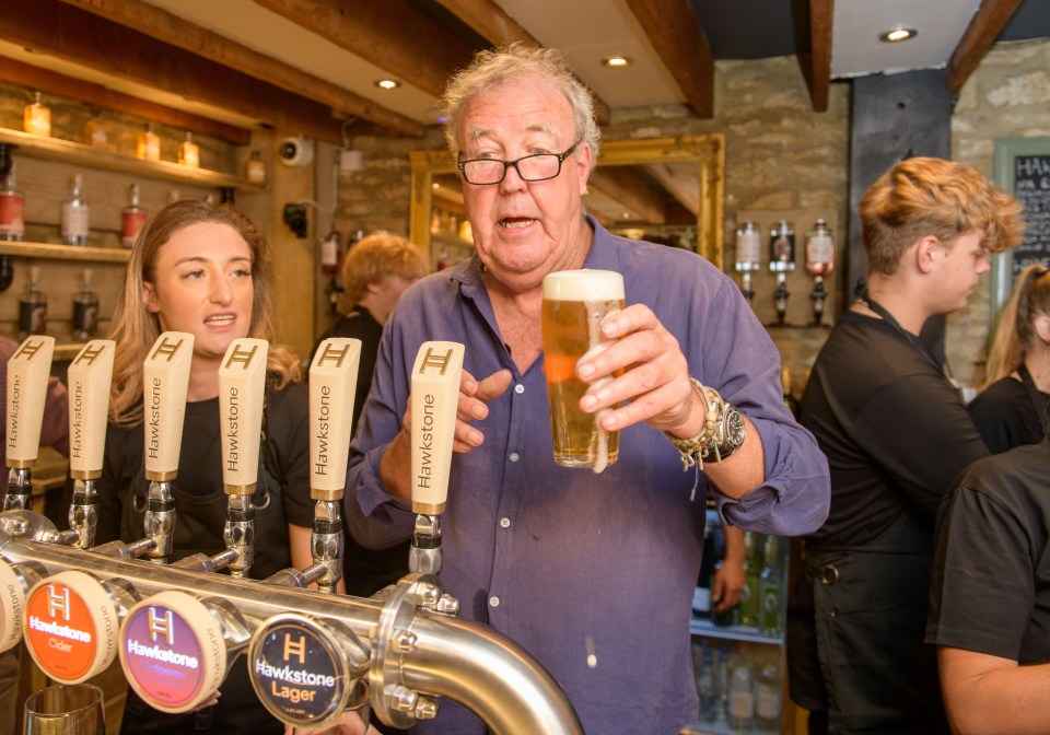 a man stands behind a bar with hawkstone beer taps