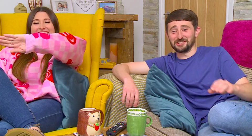 a man and a woman are sitting on a couch with a mug that has a dog on it