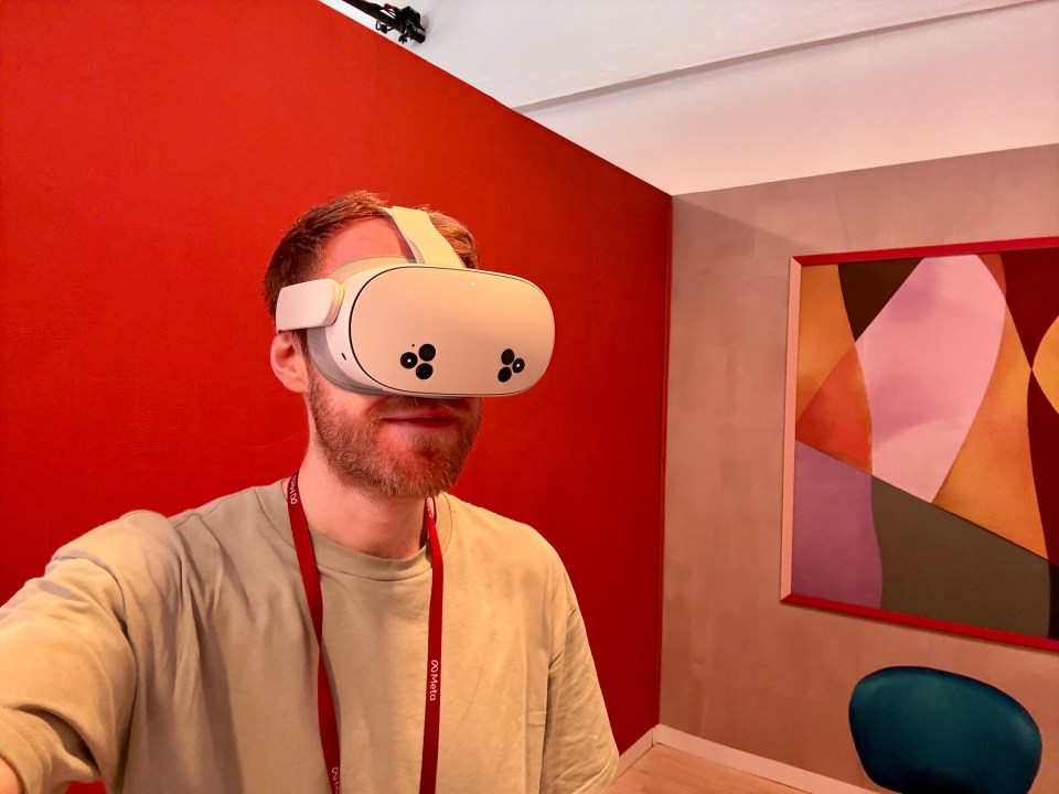 a man wearing an oculus virtual reality headset in front of a red wall