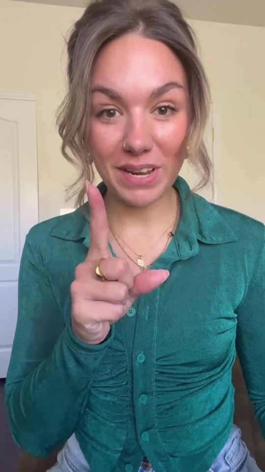 a woman in a green shirt is pointing at the camera