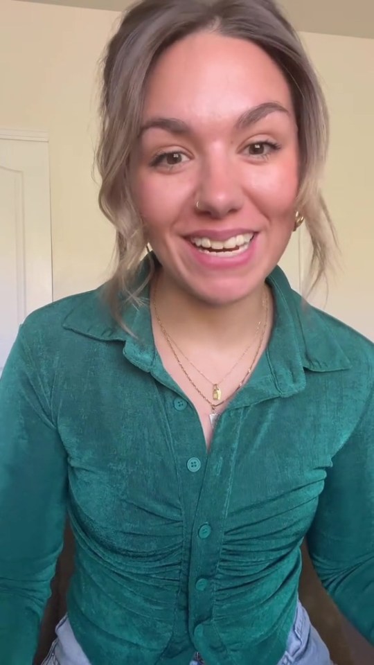 a woman wearing a green shirt and a gold necklace smiles
