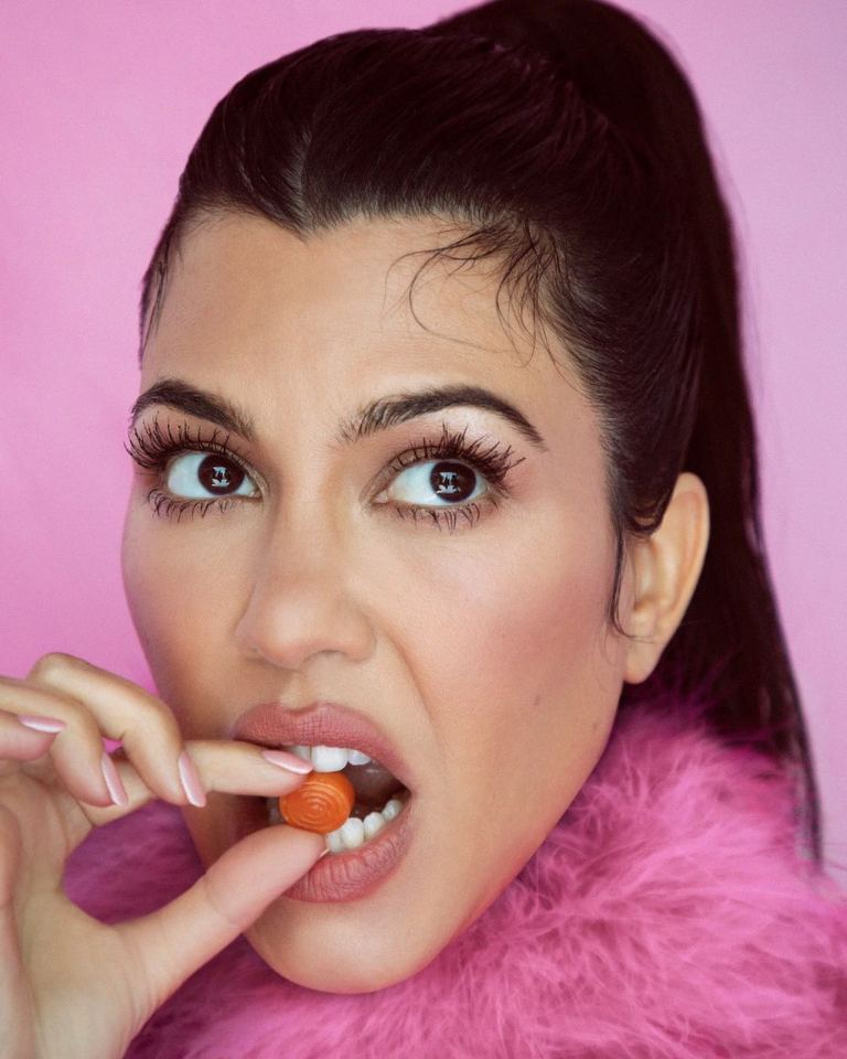 a woman in a pink fur coat is eating a lollipop