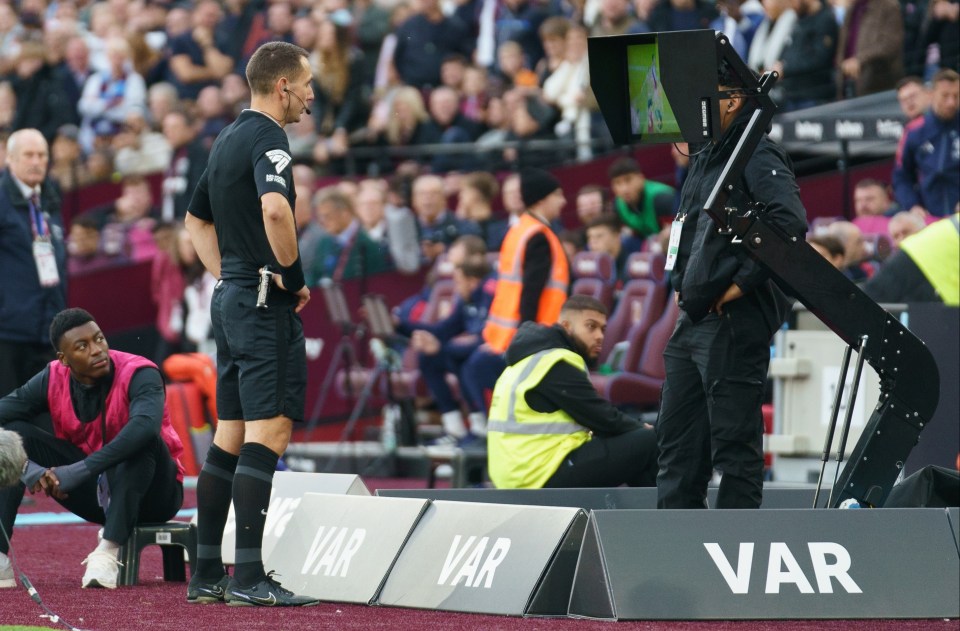 a referee stands in front of a var sign