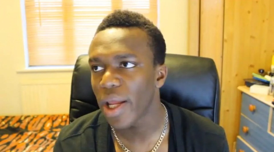 a man wearing a chain around his neck looks at the camera