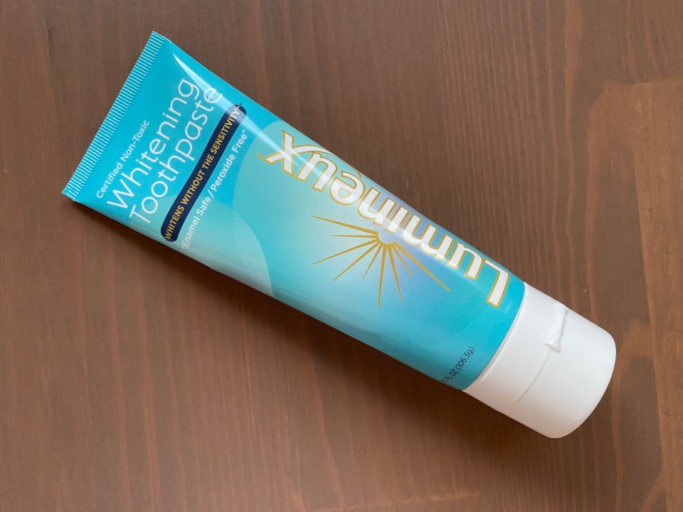 a tube of lumineux whitening toothpaste on a wooden table