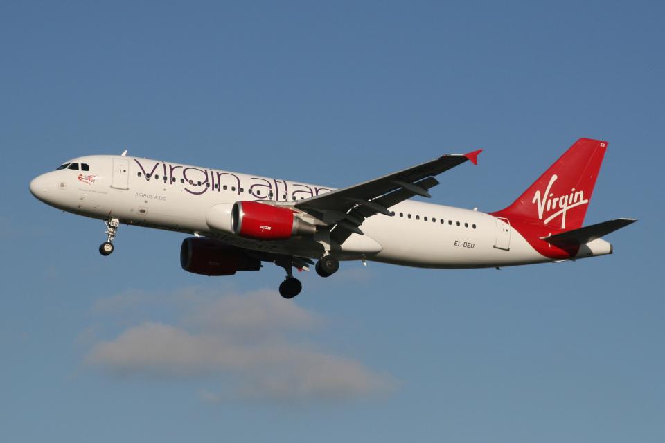 a virgin airlines plane is flying in the sky