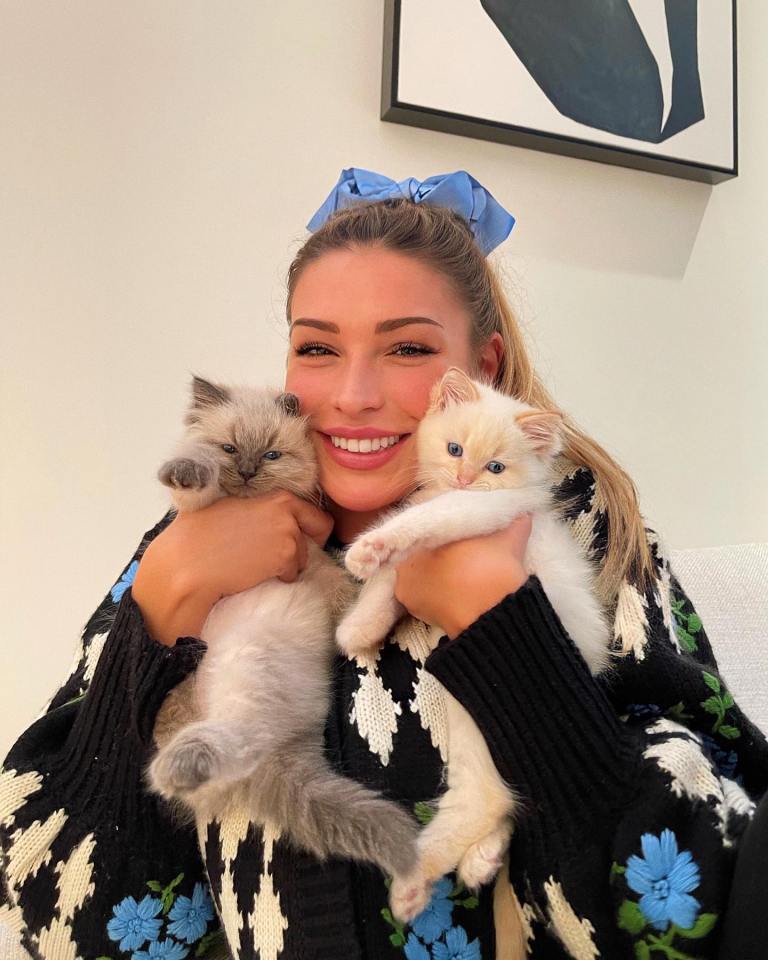 a woman in a black and white sweater is holding two kittens