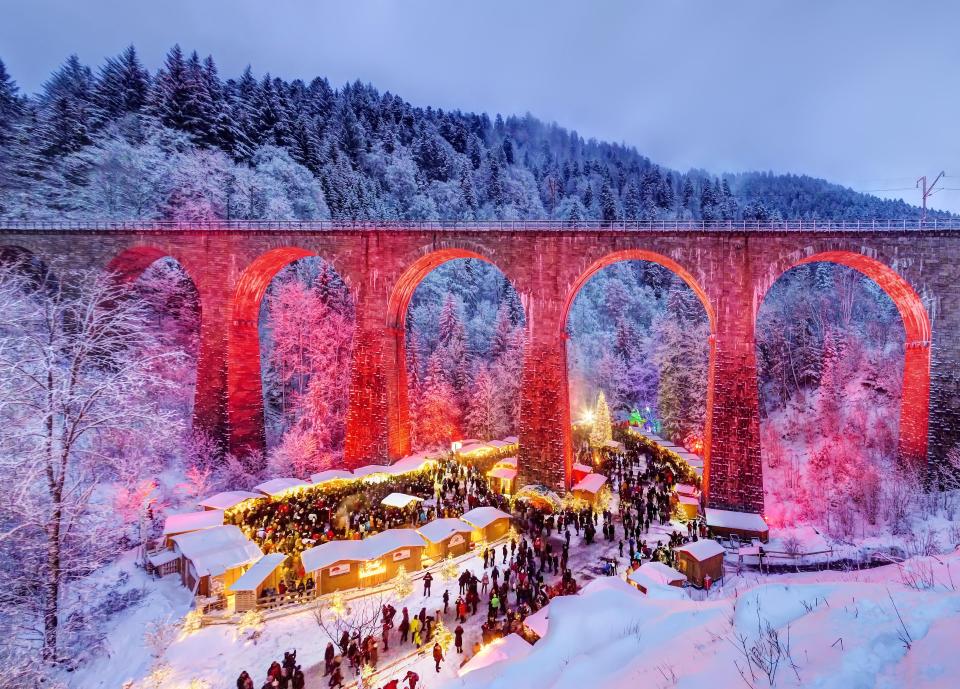 a bridge with arches is surrounded by snow covered trees