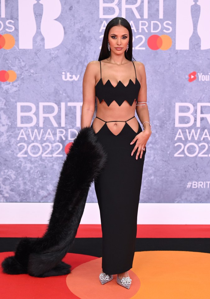 a woman stands on a red carpet at the brit awards