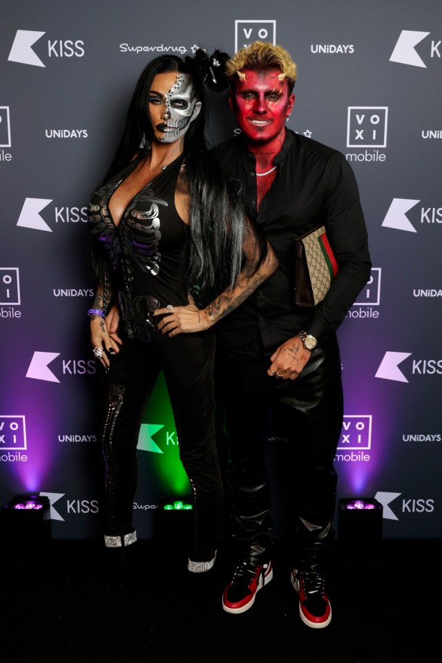 a man and a woman standing in front of a kiss sign