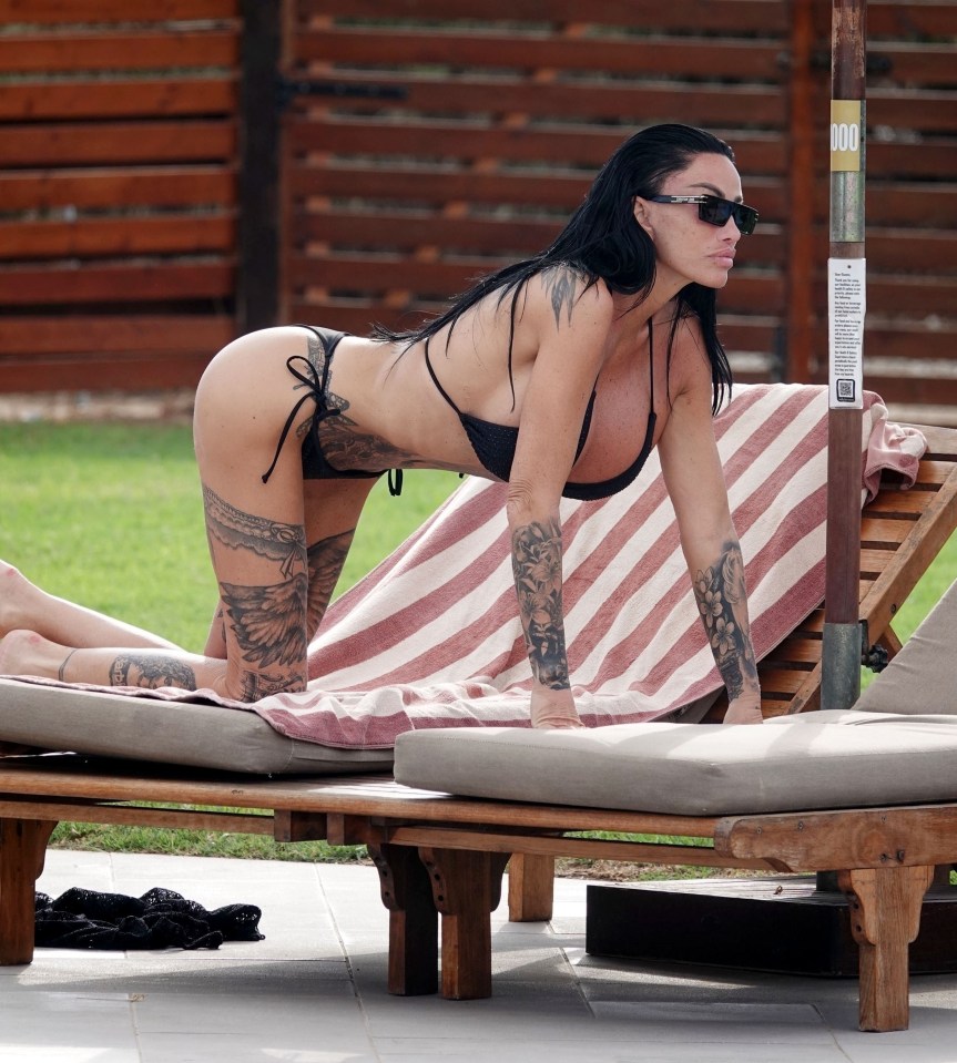 a woman in a bikini sits on a lounge chair next to a sign that says dog