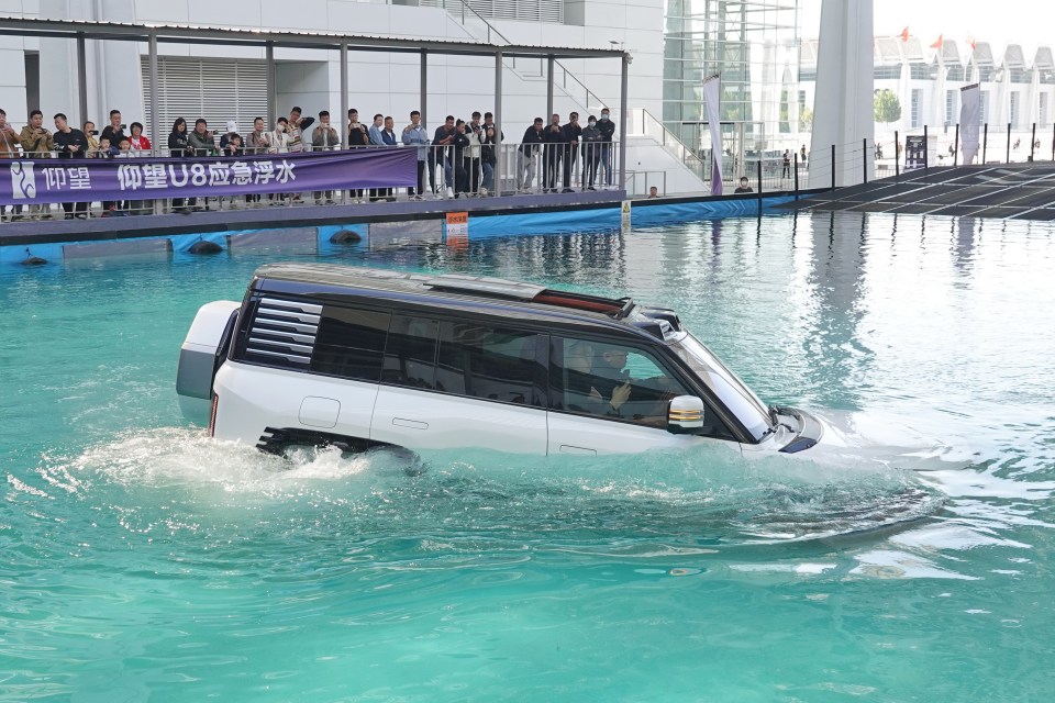 a white suv is driving through a body of water