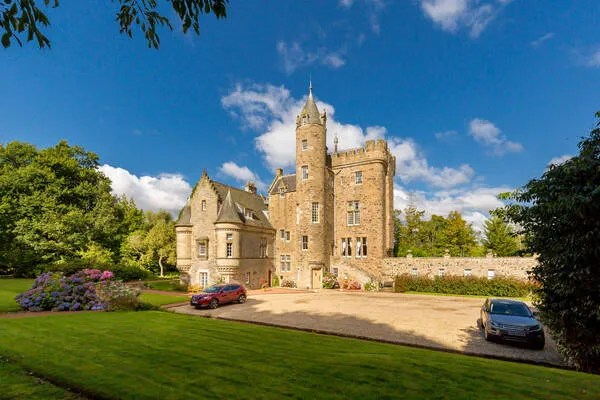 two cars are parked in front of a large castle .