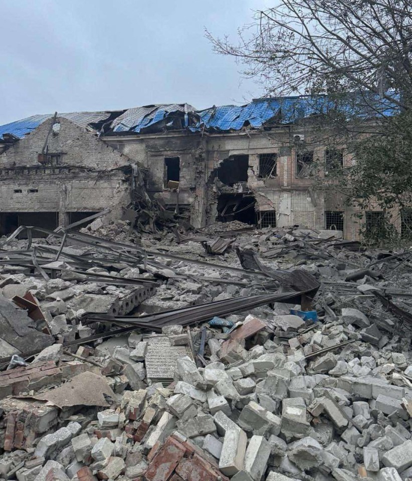 a pile of rubble in front of a building with a blue tarp on the roof