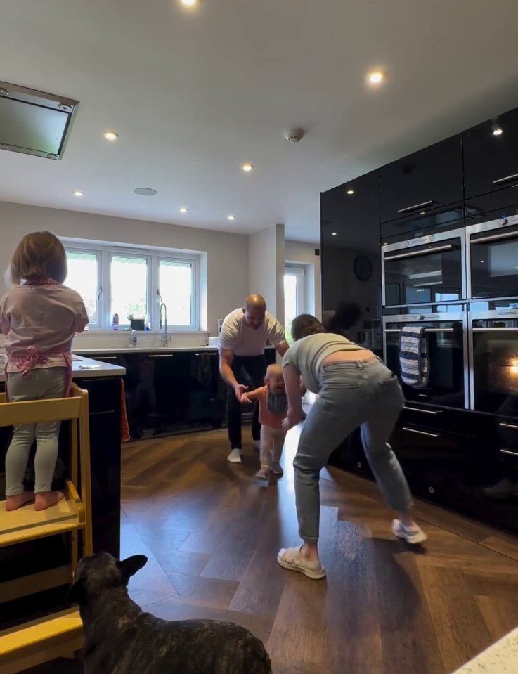 a family is playing in a kitchen with a dog