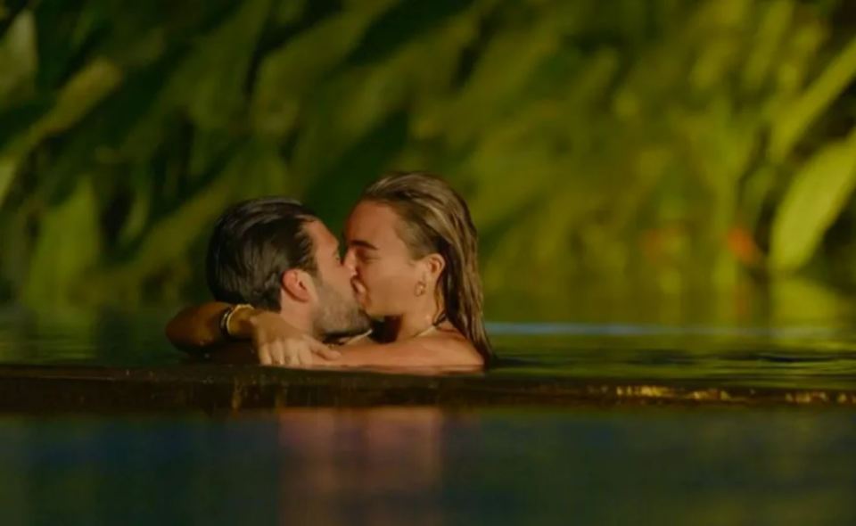 a man and a woman are kissing in a swimming pool .