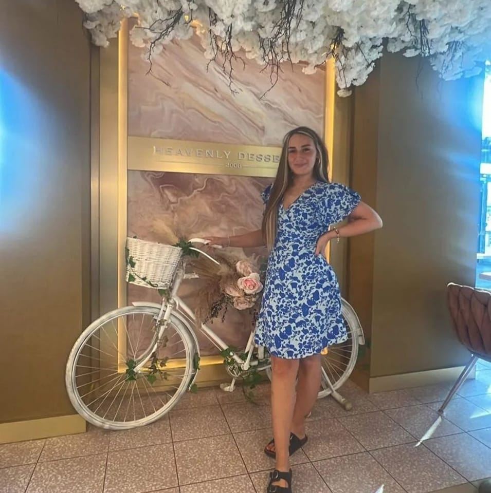 a woman in a blue dress stands next to a white bicycle