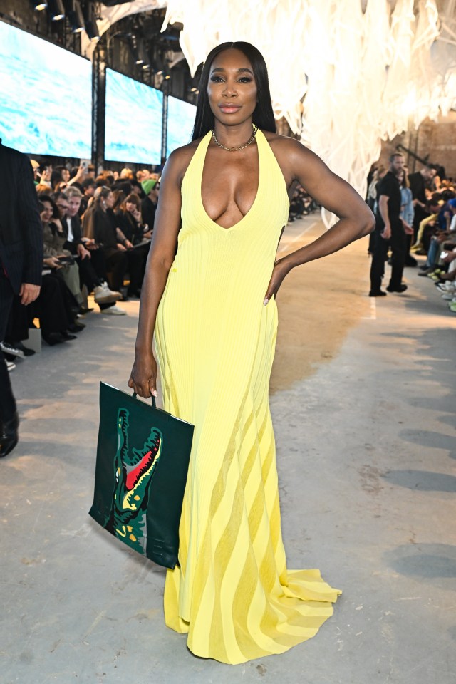 a woman in a yellow dress is holding a green bag with a crocodile on it