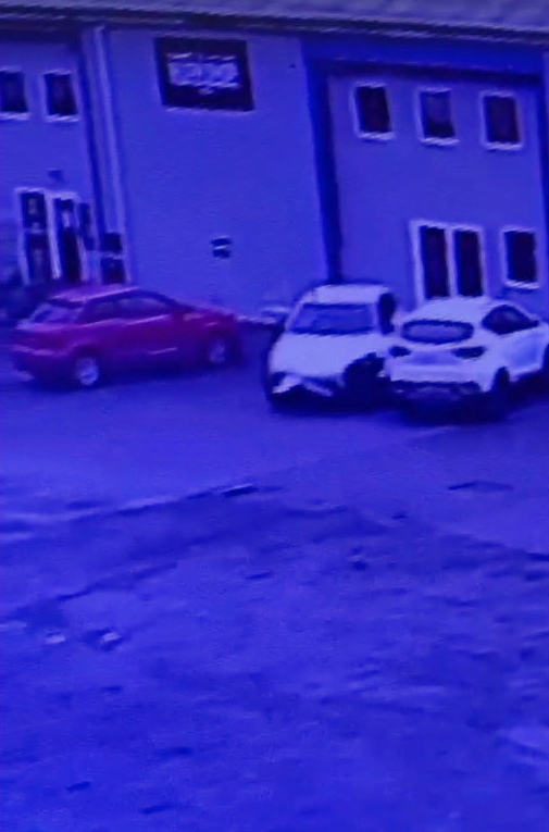 two cars are parked in front of a building with a sign that says ' tesco ' on it