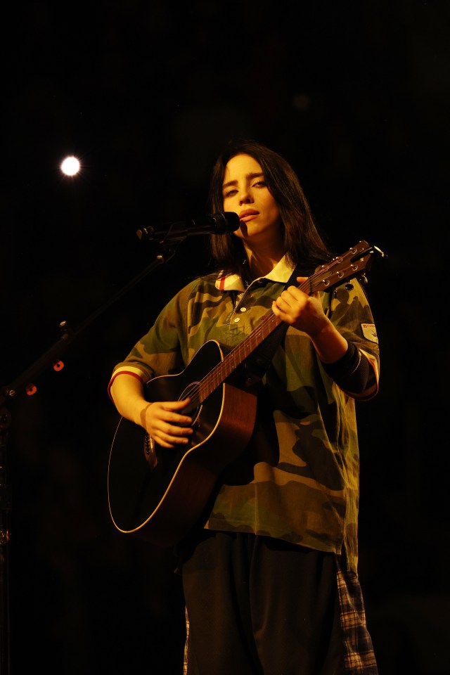 a woman singing into a microphone while holding a guitar