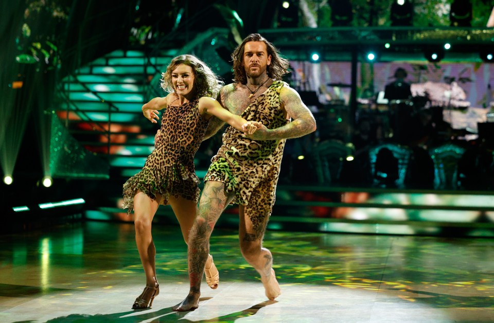 a man in a leopard print outfit is dancing with a woman