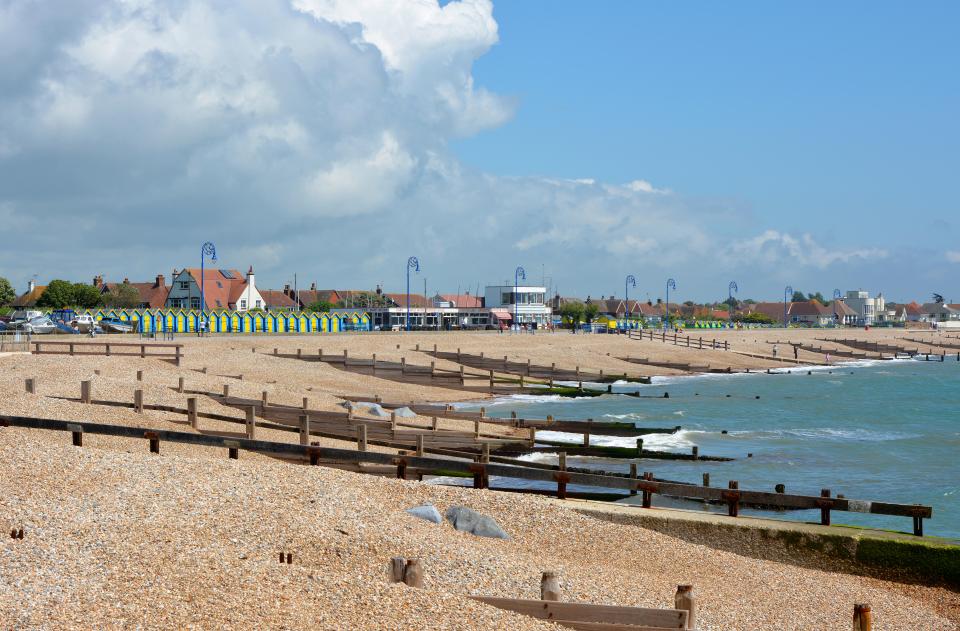 a beach with blue and yellow umbrellas in the background
