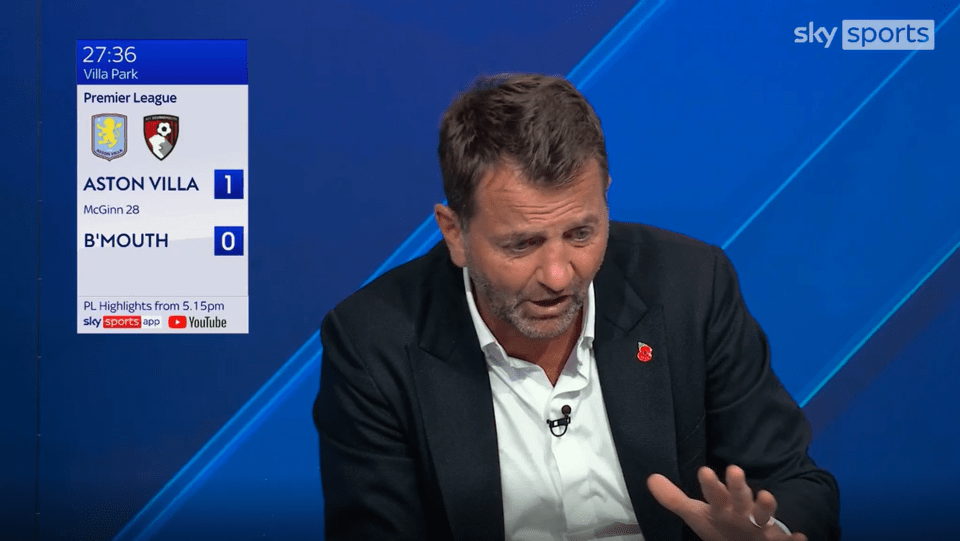 a man in a suit is sitting in front of a screen that says sky sports