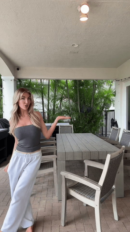 a woman standing on a patio with a table and chairs