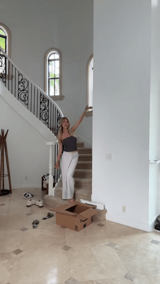 a woman stands on a set of stairs next to a cardboard box that says amazon on it