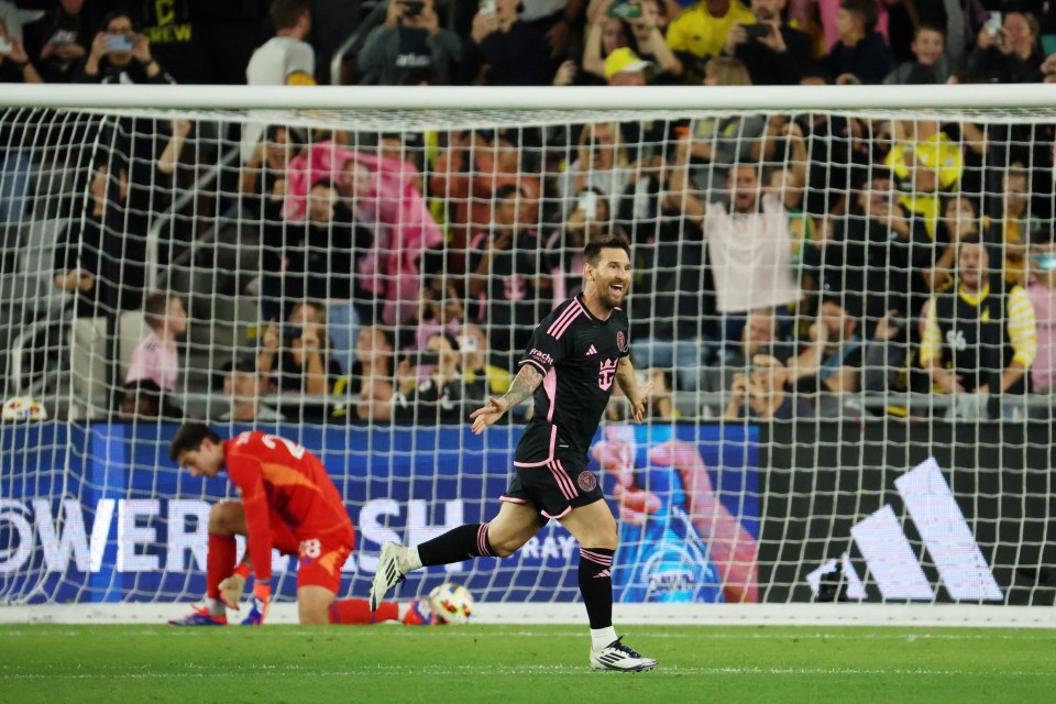 a soccer player wearing a black adidas jersey runs towards the goal